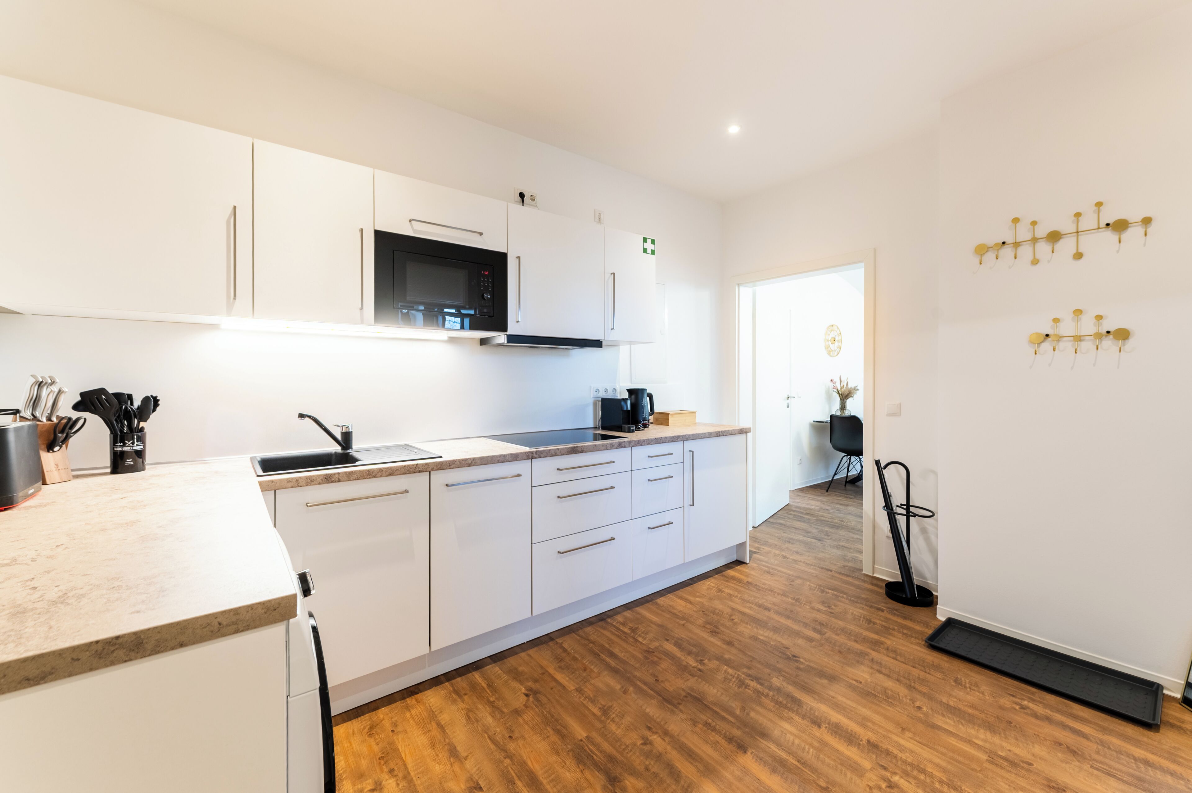 A modern kitchen with white cabinetry, a microwave, and a coffee maker.
