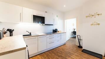 A modern kitchen with white cabinetry, a microwave, and a coffee maker.