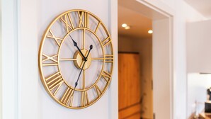 A round wall clock with Roman numerals and a pendulum. - Vita Aurum Elbe-Apartments Neustadt  (Dresden)