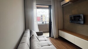 Un salon moderne avec un canapé, un téléviseur et un balcon.