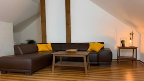 Una sala de estar moderna con un sofá seccional, una mesa de centro de madera y una mesita auxiliar con una lámpara.