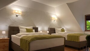 A bedroom with two beds, a wooden nightstand, a lamp, and a window with blinds. - Nature-Inspired 100 m² Apartment with Fenced Garden, Terrace & Wi-Fi – Dog-Friendly (Neuzelle)