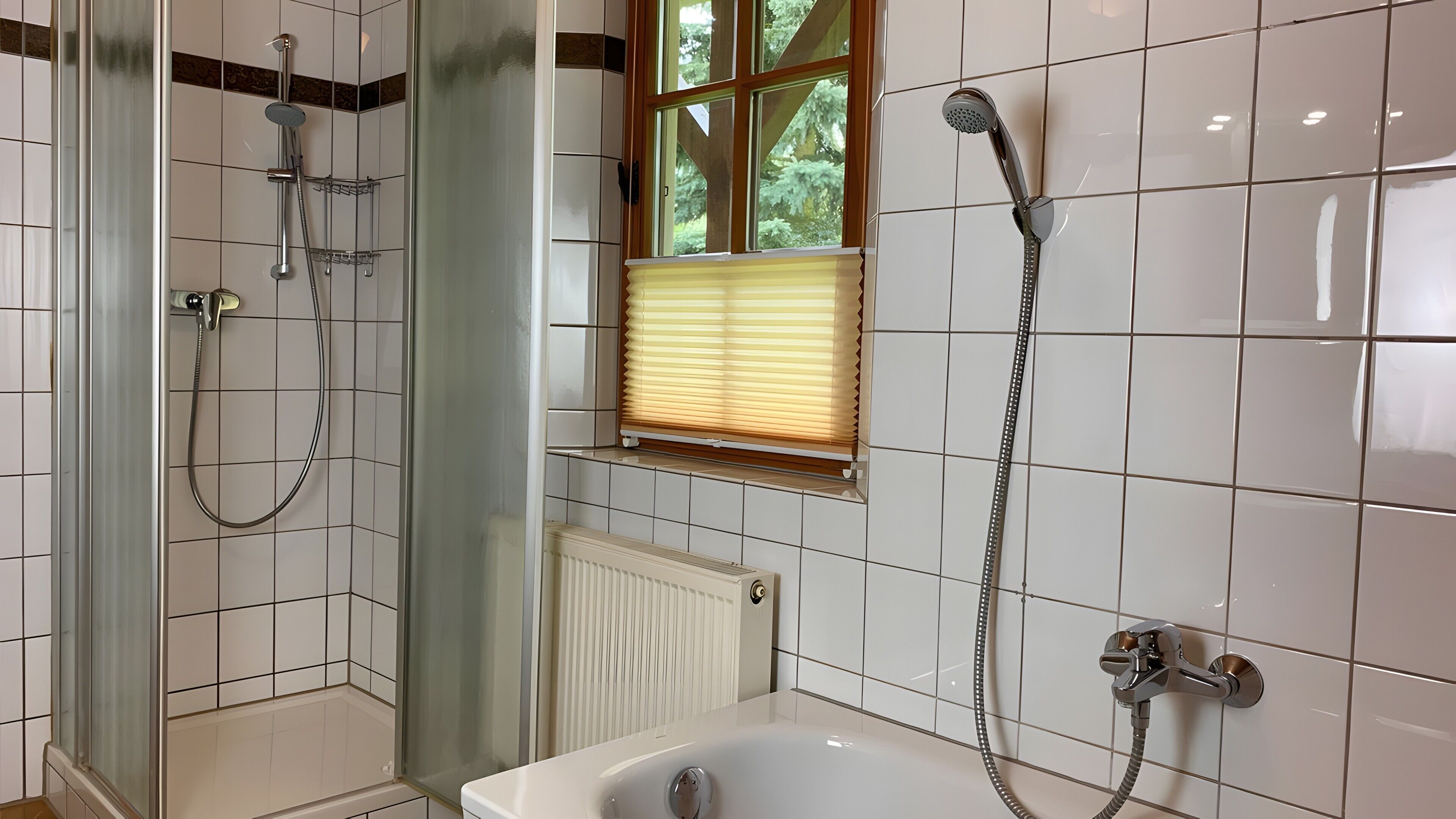 A bathroom with a glass-enclosed shower, a window with blinds, a bathtub, and a radiator.