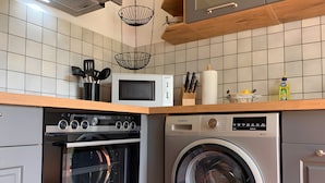 A kitchen with a microwave, oven, and washing machine. - Nature-Inspired 100 m² Apartment with Fenced Garden, Terrace & Wi-Fi – Dog-Friendly (Neuzelle)