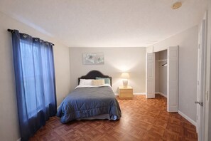 A bedroom with a bed, a nightstand, a wall art piece, and a door leading to another room. - 3BR Home Minutes to the Beach (Boynton) (Boynton Beach)