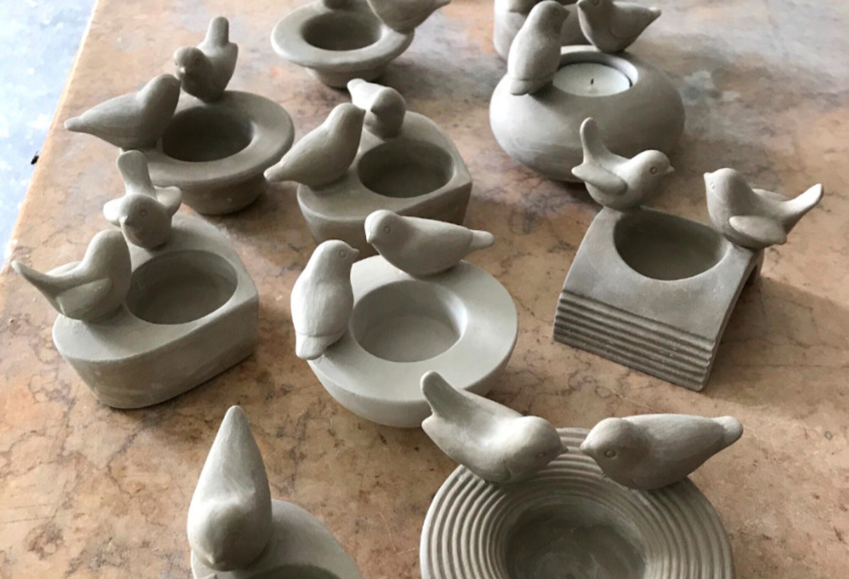 A collection of ceramic bird-shaped containers on a marble surface.