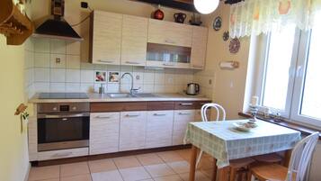A kitchen with a stove, oven, sink, and a dining table with chairs.