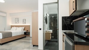 Een moderne hotelkamer met een bed, nachtkastje en een douchecabine met glazen wanden.