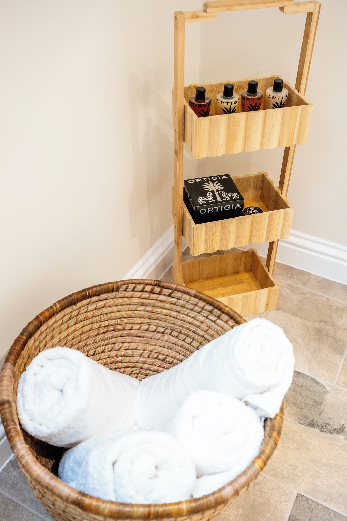 Een houten plank met flessen en een rieten mand met opgerolde handdoeken.