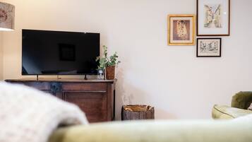 A room with a flat-screen TV on a wooden cabinet, a wicker basket, and framed artwork on the wall.
