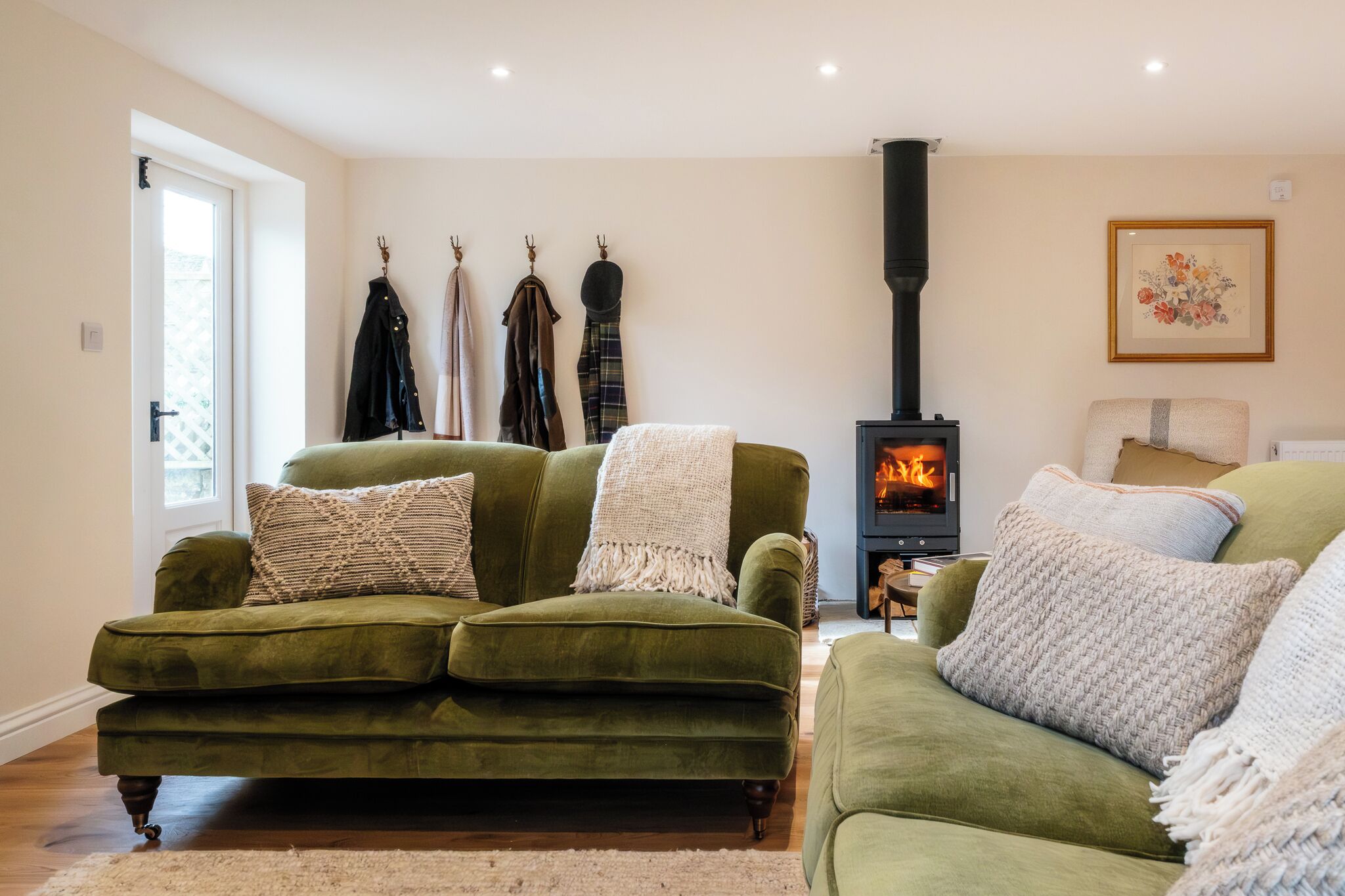 Un salon chaleureux avec un canapé vert, une cheminée et une porte donnant sur l’extérieur.