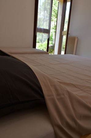Un lit avec une couvre-lit beige et un oreiller de couleur foncée.