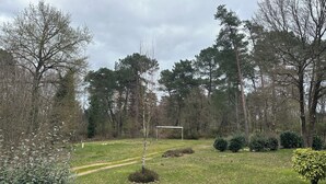 En park med ett fotbollsmål, träd och en klar himmel.