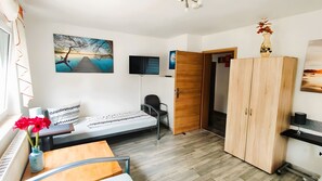 Une chambre à coucher avec un lit, une armoire en bois, une télévision et un tableau accroché au mur.