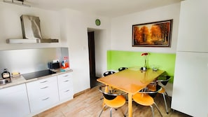 Une cuisine moderne avec des meubles blancs, un plan de travail noir et une table à manger en bois, assortie de chaises orange.