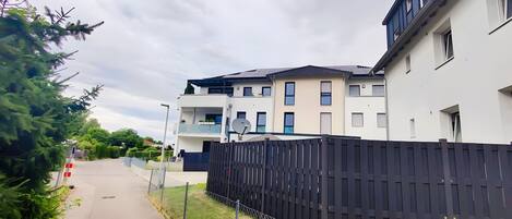 Un immeuble résidentiel à l’architecture moderne, doté de balcons, d’une antenne parabolique et d’une entrée sécurisée par un portail.