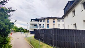 Un edificio residencial de diseño moderno, con balcones, antena parabólica y entrada protegida.