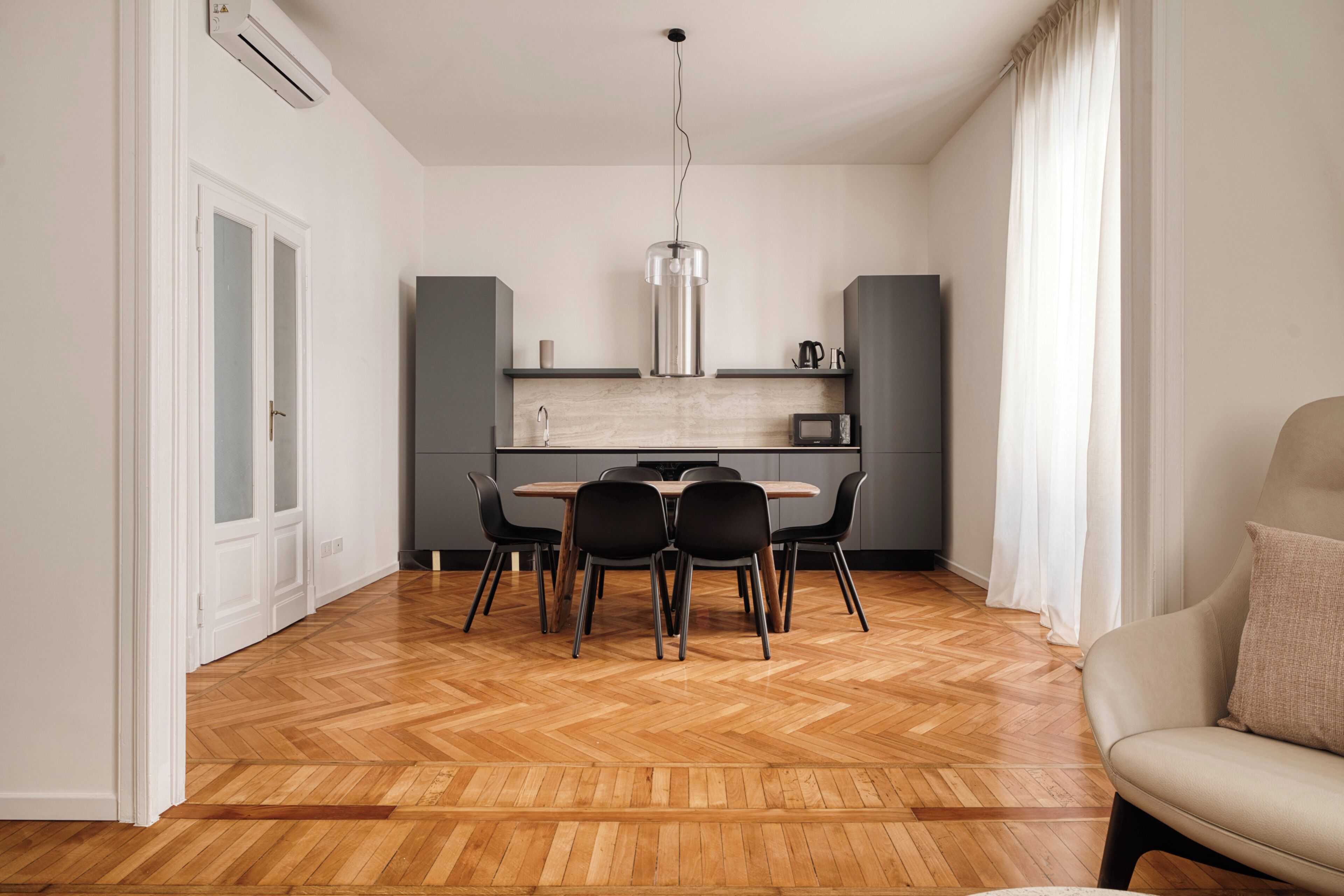 A modern kitchen with a dining table, chairs, and a pendant light.