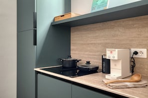 Cocina moderna con cocina por inducción negra, cafetera y cuchara de madera sobre la encimera.