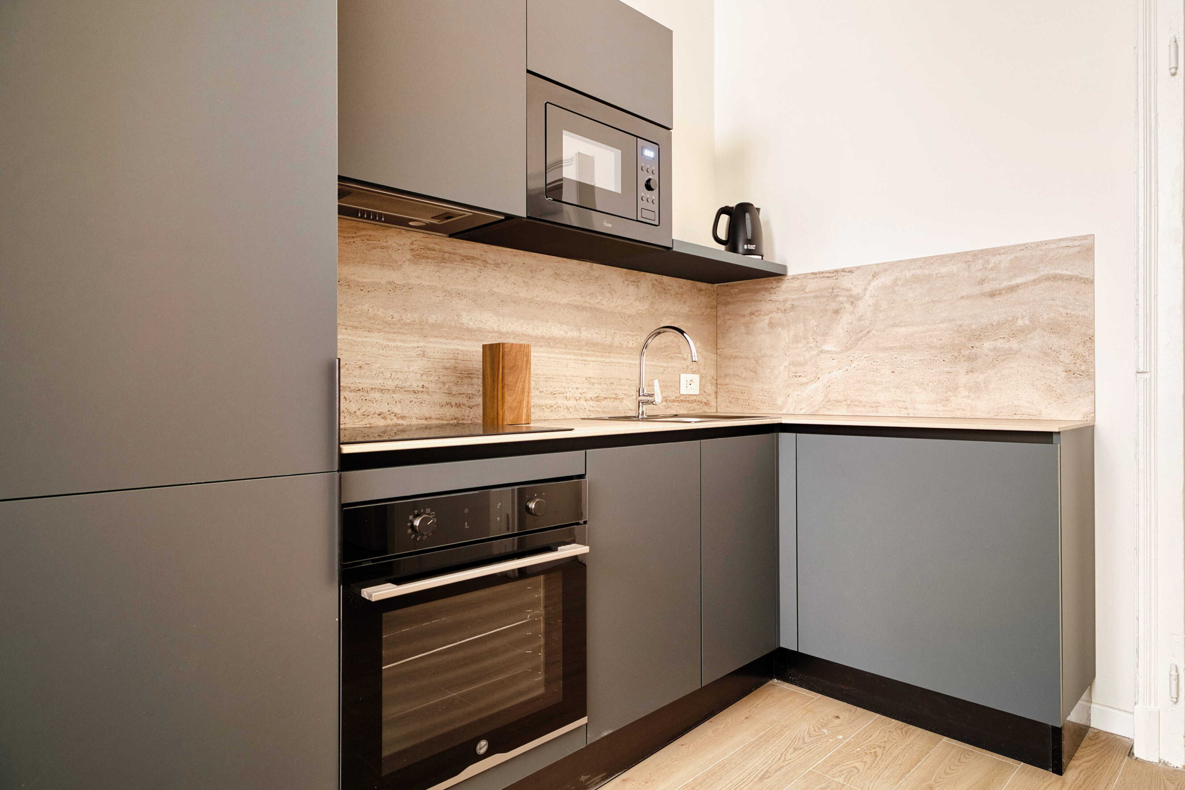 A modern kitchen with a built-in oven, microwave, and a coffee maker on a shelf.