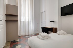 Una habitación de hotel con una cama, un escritorio, una silla, un televisor y un armario.