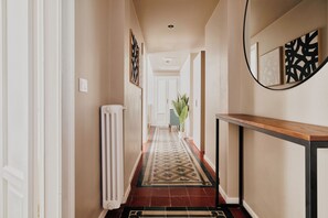 A hallway with a radiator, a patterned rug, a potted plant, and framed artwork on the walls. - Elegant Flats near Guastalla Gardens (Milan)
