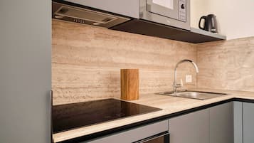 A modern kitchen with a black countertop, stainless steel sink, and a built-in microwave.