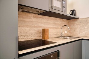 A modern kitchen with a black countertop, stainless steel sink, and a built-in microwave. - Elegant Flats near Guastalla Gardens (Milan)