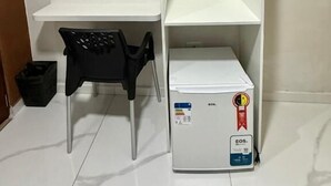 Et hvidt skrivebord med stol, et hvidt reolsystem og et hvidt køleskab.