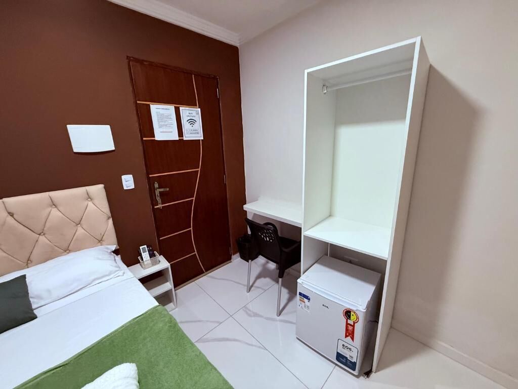 Una habitación de hotel con cama, escritorio, armario y espejo.