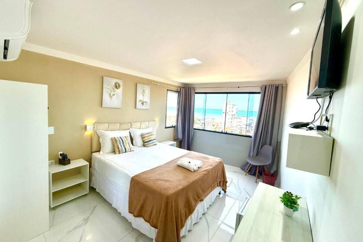 Une chambre d’hôtel équipée d’un lit, d’un bureau, d’une chaise, d’une télévision et d’une fenêtre donnant sur la ville.