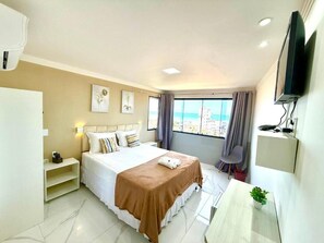 Een hotelkamer met een bed, een bureau, een stoel, een televisie en een raam met uitzicht over de stad.