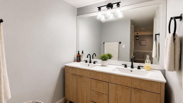 A bathroom with a double sink, wooden vanity, and a large mirror. - University Condo (Gainesville)