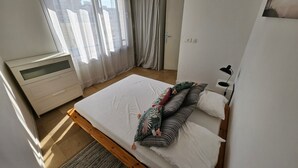 A bedroom with a bed, a bedside table, a lamp, a window with curtains, and a wardrobe. - Central Juan-les-Pins Colombier 1-Bedroom with Sea View, Parking (Antibes)