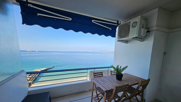 A balcony with a view of the sea, a table with chairs, and an air conditioning unit. - Central Juan-les-Pins Colombier 1-Bedroom with Sea View, Parking (Antibes)