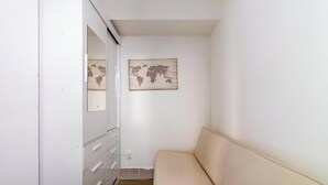 A narrow hallway with a beige sofa, a white dresser, and a world map artwork on the wall. - 3-bedroom Apt in Oceanfront Building Adlb0203 (Cabo Frio)