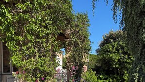 A garden with flowering plants and a building with a window. - Beautiful Villa in private estate with 5 bedrooms, swimming pool, panoramic view (Villeneuve-Loubet)