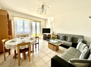 Ein Wohnzimmer mit Esstisch, Sofa, Fernseher und Deckenventilator.