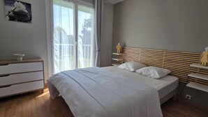 A bedroom with a bed, a dresser, a nightstand, and a window with curtains. - Beautiful, bright, renovated apartment in the center of Concarneau with private parking (Concarneau)