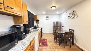 A compact kitchen with wooden cabinets, a stainless steel refrigerator, a microwave, and a coffee maker.