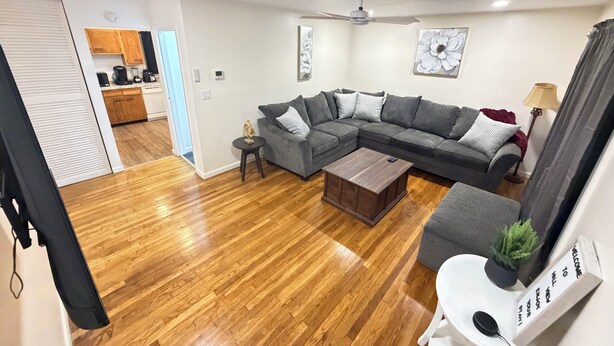 A living room with a sectional sofa, a coffee table, a ceiling fan, and a small side table.