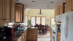 A kitchen with wooden cabinets, a dining area with a table and chairs, a refrigerator, and a microwave.