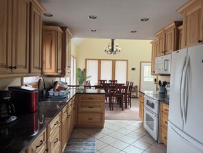 Eine Küche mit Holzschränken, ein Essbereich mit Tisch und Stühlen, ein Kühlschrank und eine Mikrowelle.