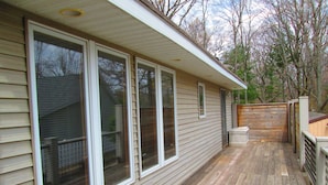 A wooden deck with a railing, large windows, and a door.