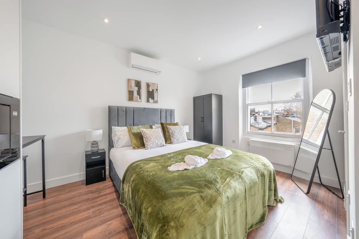 A modern hotel room with a bed, a desk, a wardrobe, and a window with a view.