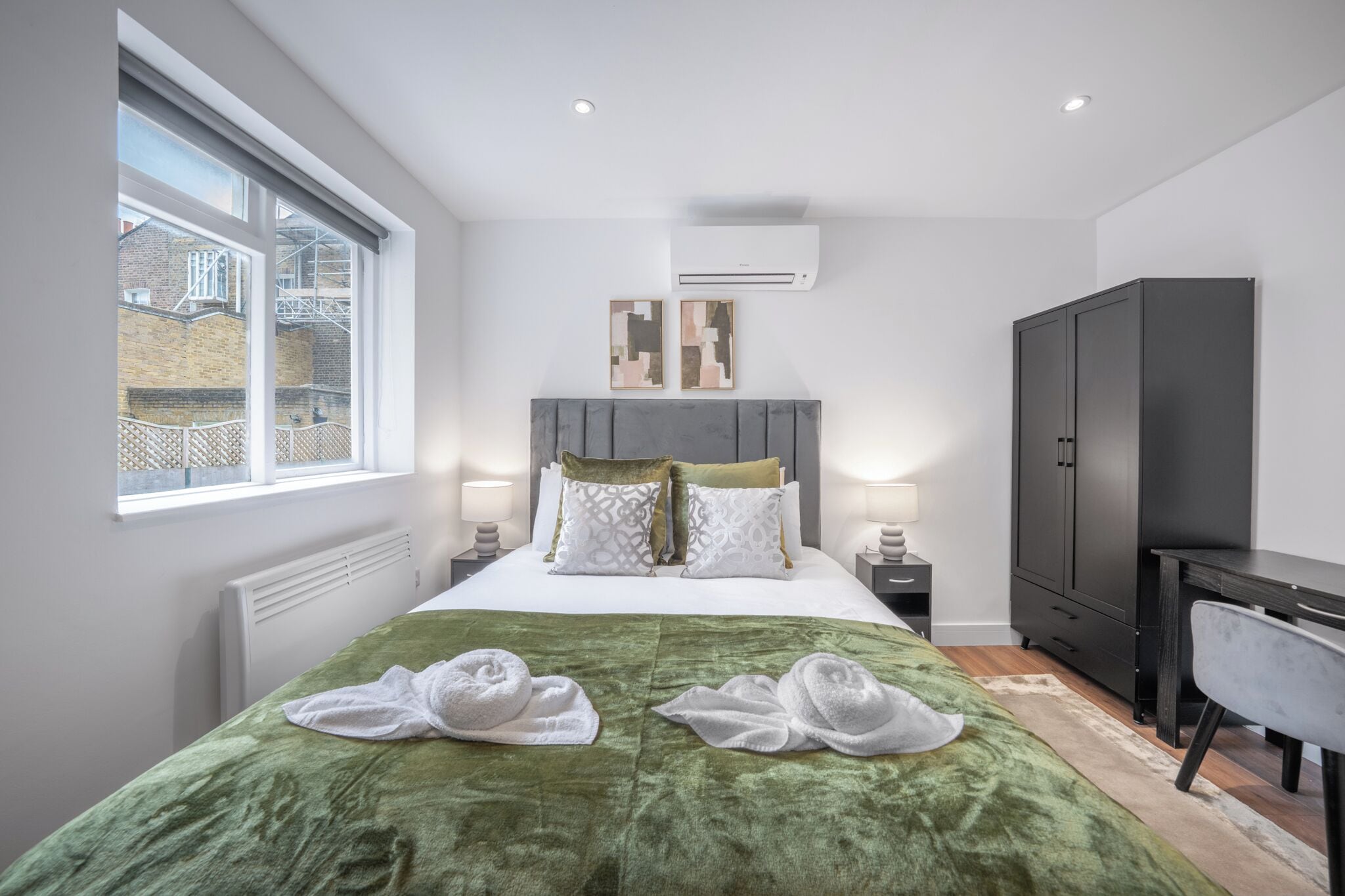 Una habitación de hotel moderna con una cama grande, un escritorio, un armario y una ventana con vistas al exterior.