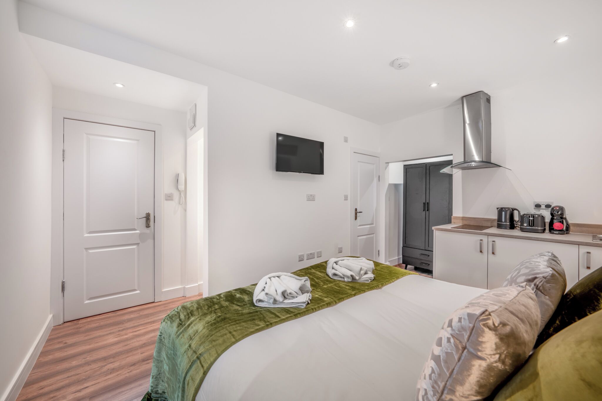 Ein Hotelzimmer mit Bett, Fernseher, Küchenzeile und Bad.