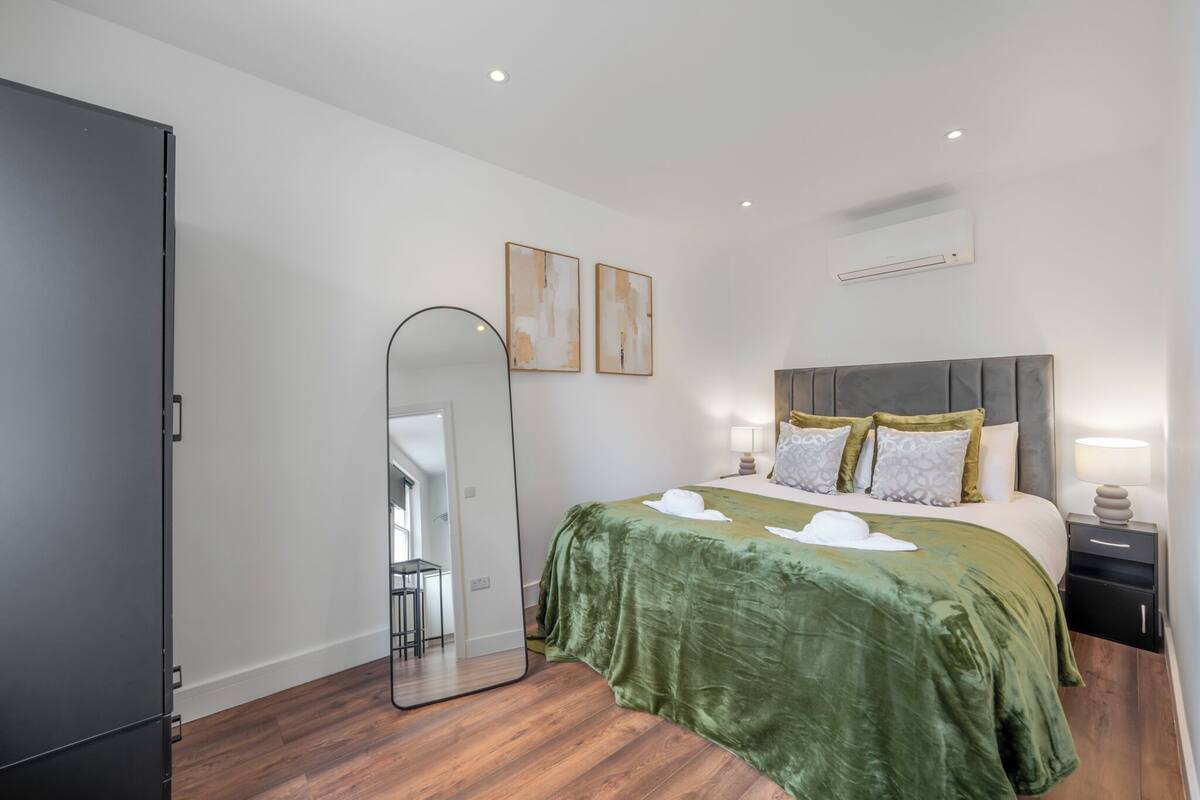 A bedroom with a bed, bedside tables, a mirror, and artwork on the wall.