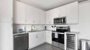 A modern kitchen with white cabinets, stainless steel appliances, a microwave, oven, and dishwasher. - Landing Apartments near Dallas Medical District (Dallas)
