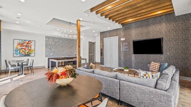 A modern living room with a sectional sofa, a dining area with a round table, and a kitchen in the background. - Landing Apartments near Dallas Medical District (Dallas)